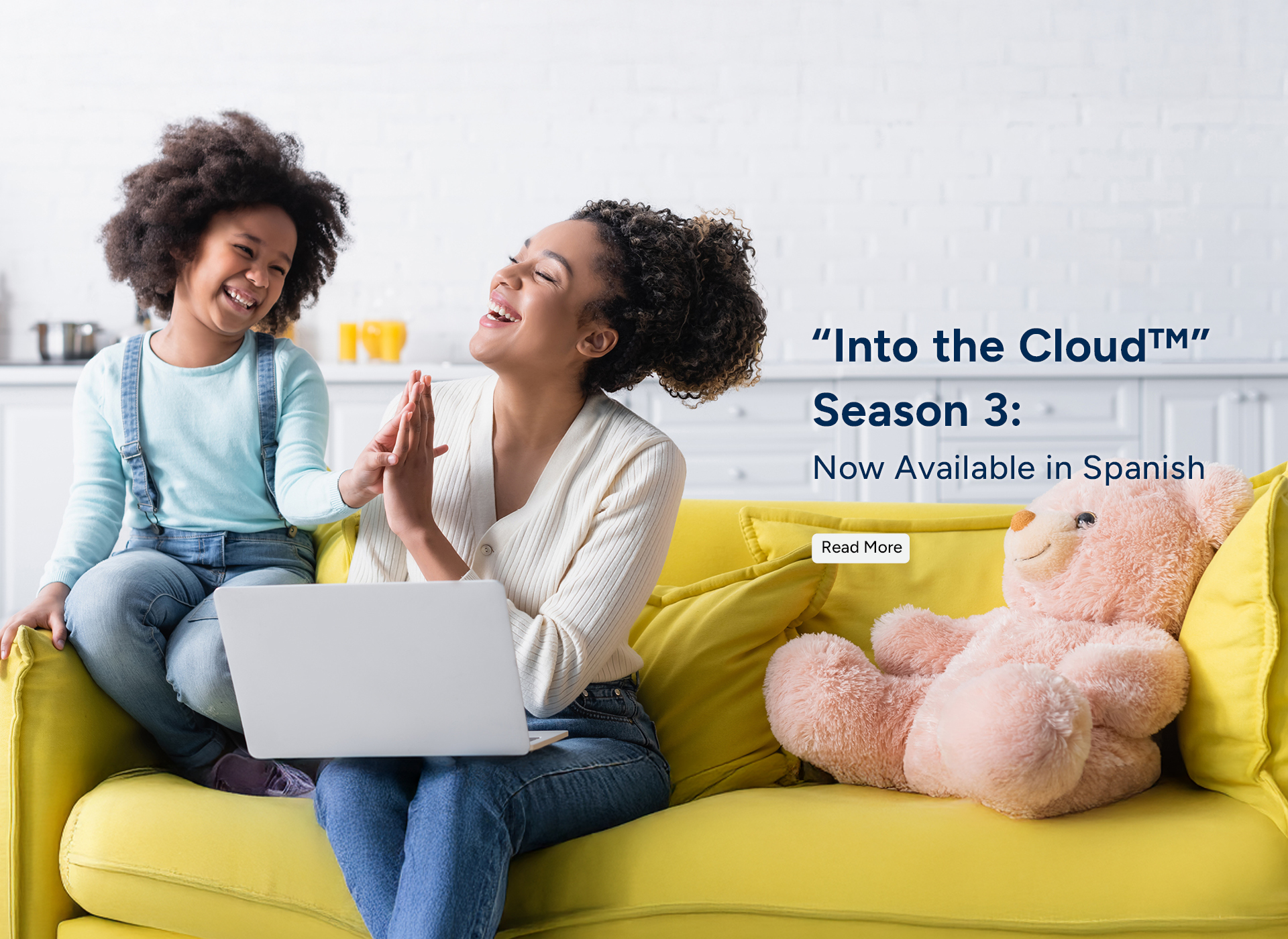 hispanic mom and young daughter sit on yellow couch with laptop out, smiling